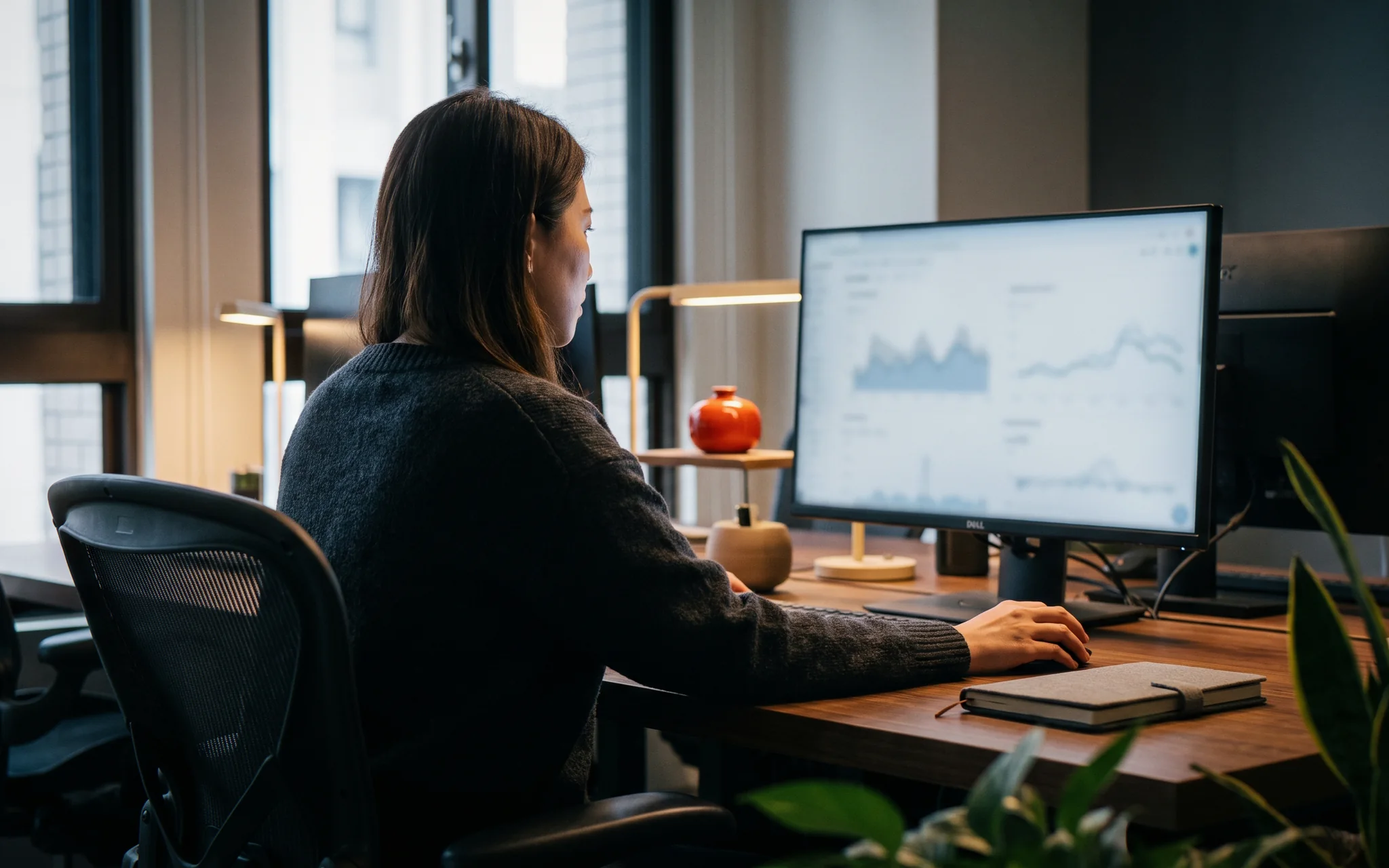 A marketer at her desk reading charts on a large monitor